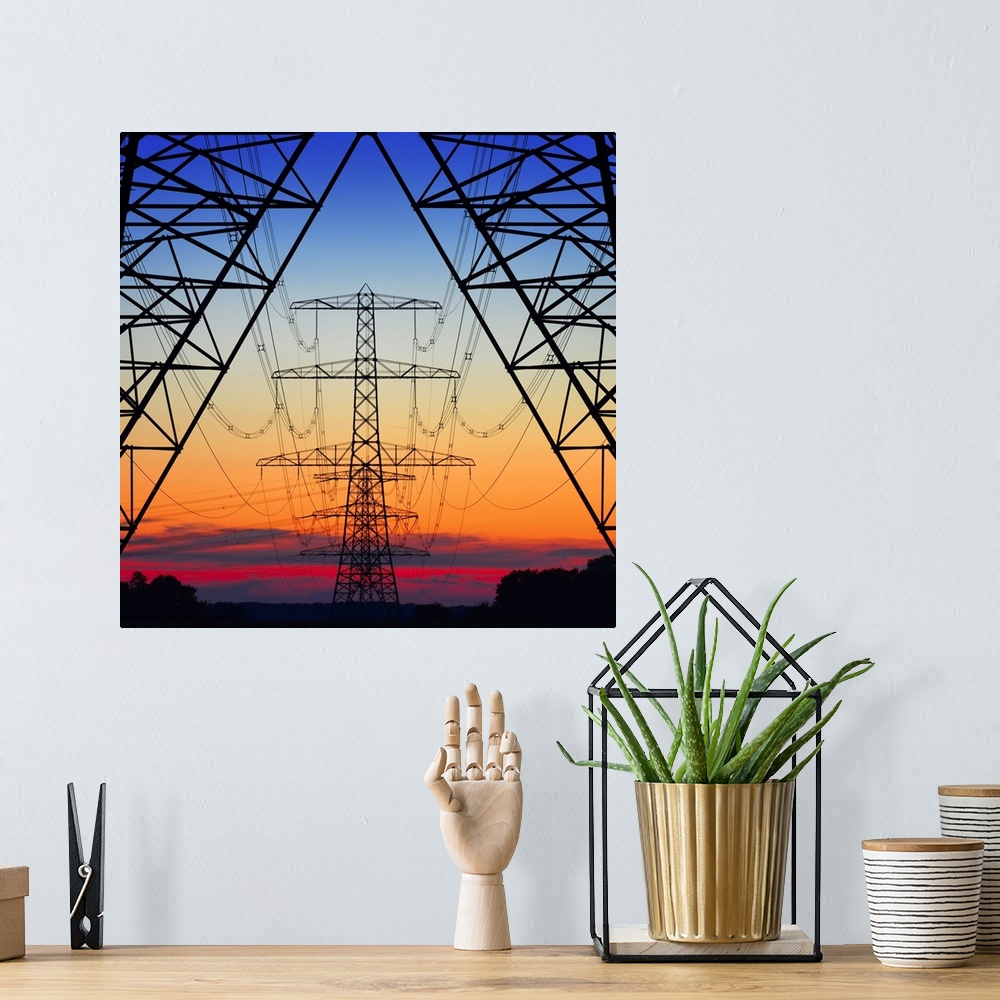 A bohemian room featuring Looking the center of electrical pylons silhouetted in the setting sun behind them.