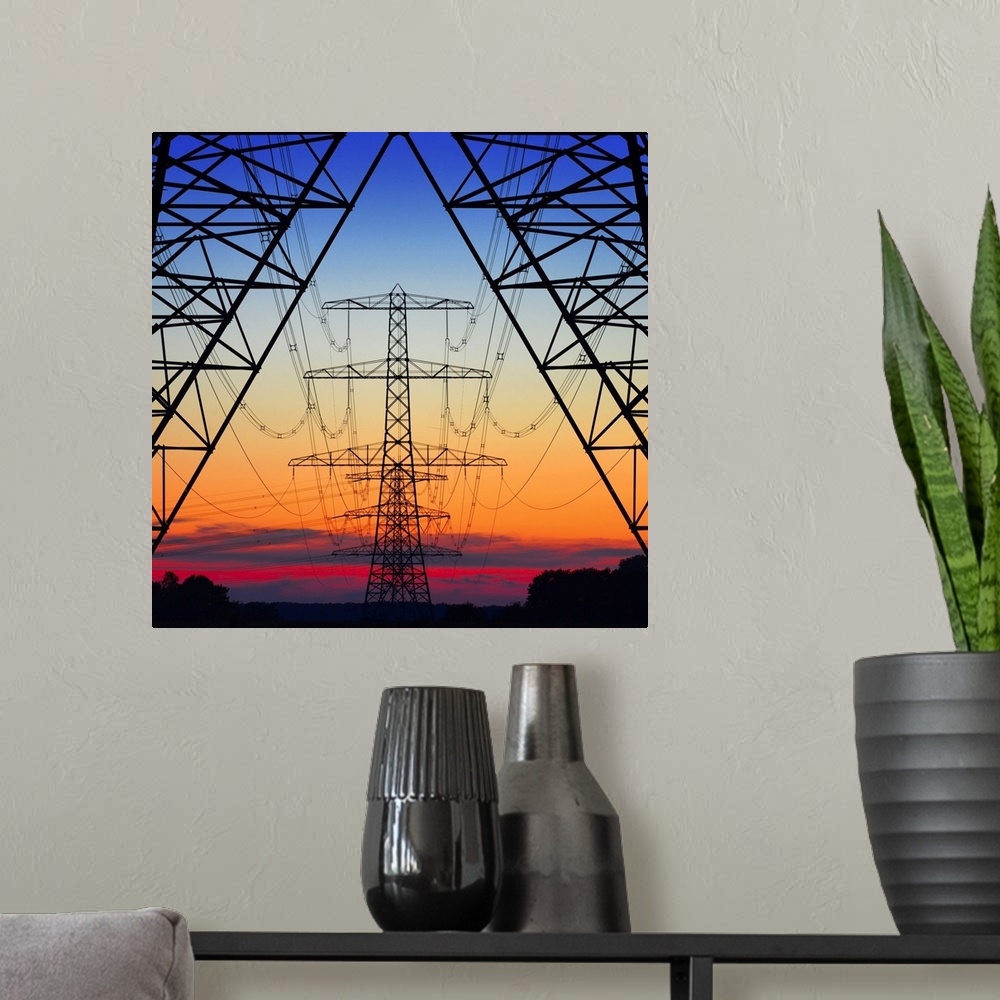 A modern room featuring Looking the center of electrical pylons silhouetted in the setting sun behind them.