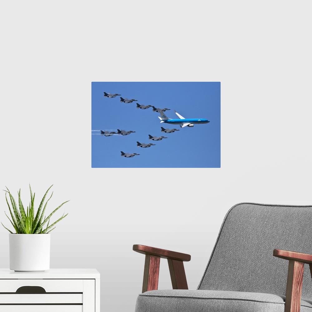 A modern room featuring A fleet of grey jets fly in formation around a blue commercial airliner.