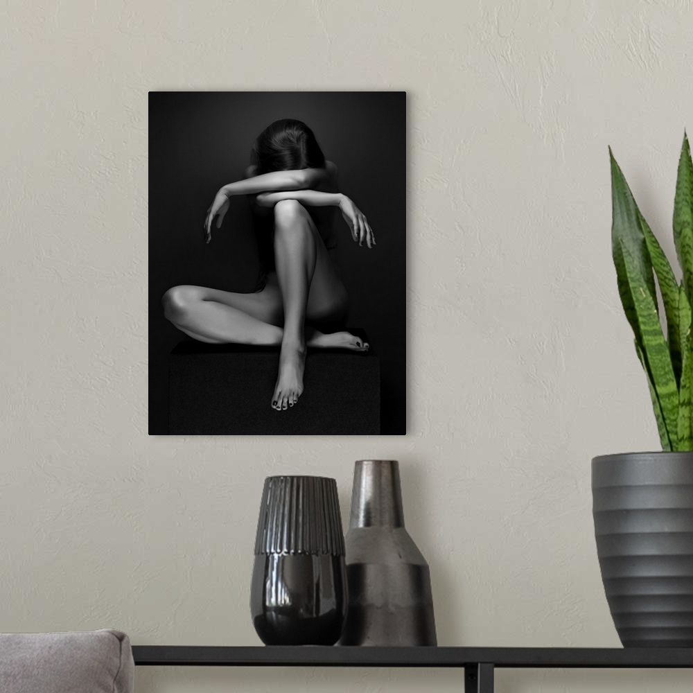 A modern room featuring Black and white fine art photograph of a woman sitting down, creating angles with her body, resem...