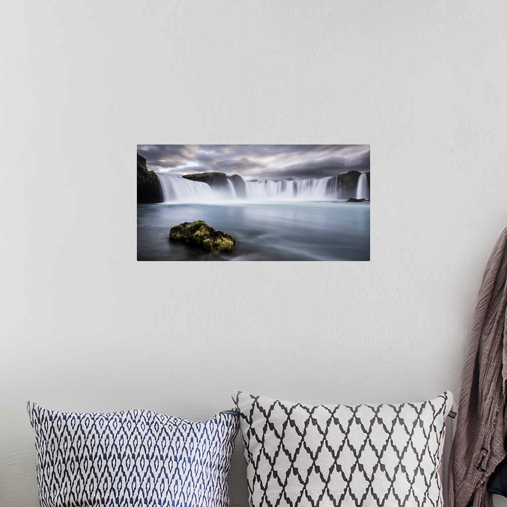 A bohemian room featuring A mossy rock in the water below Godafoss Waterfall, Iceland.