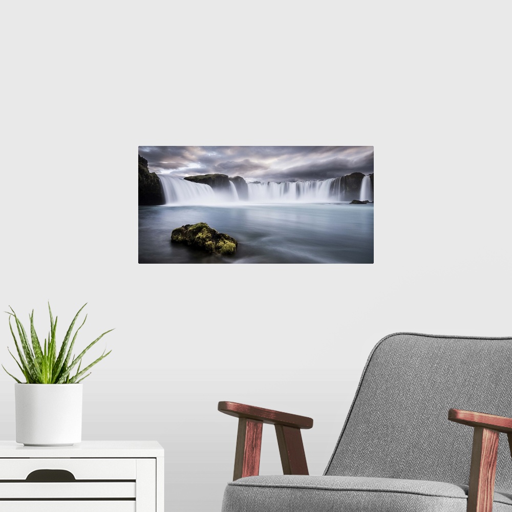 A modern room featuring A mossy rock in the water below Godafoss Waterfall, Iceland.