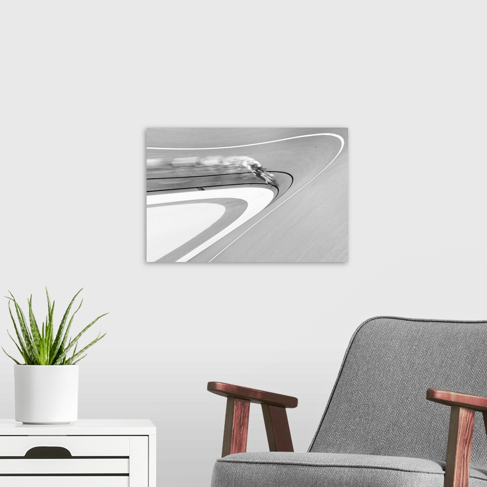 A modern room featuring Black and white image of a cyclist in a velodrome coming around a curve.