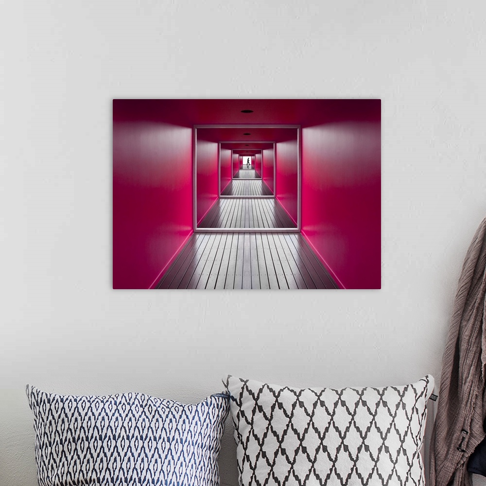 A bohemian room featuring A square shaped hallway with bright pink walls, and a figure at the exit.