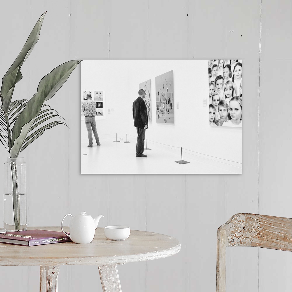 A farmhouse room featuring A man in an art gallery looks at figurative artwork on the wall.