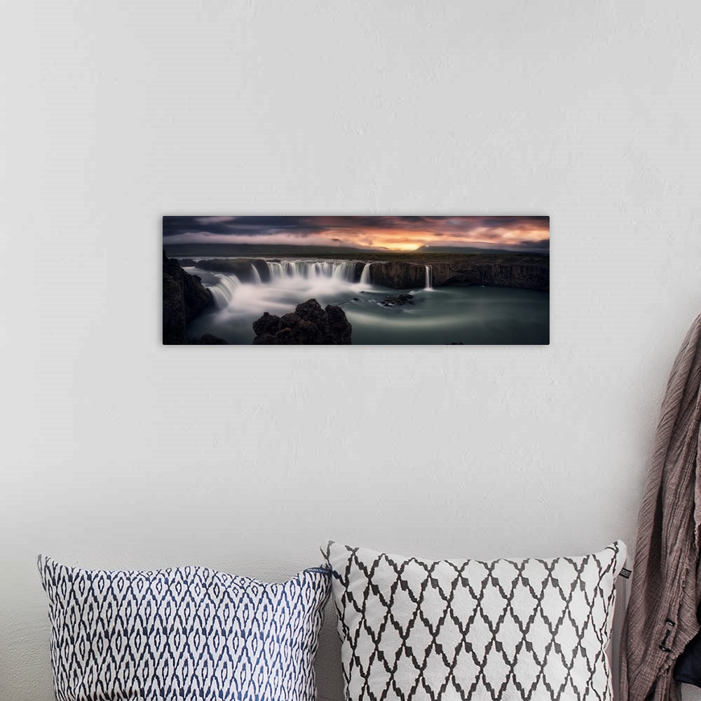 A bohemian room featuring An intense photograph of a waterfall curtain with mountains and dramatic clouds in the distance.