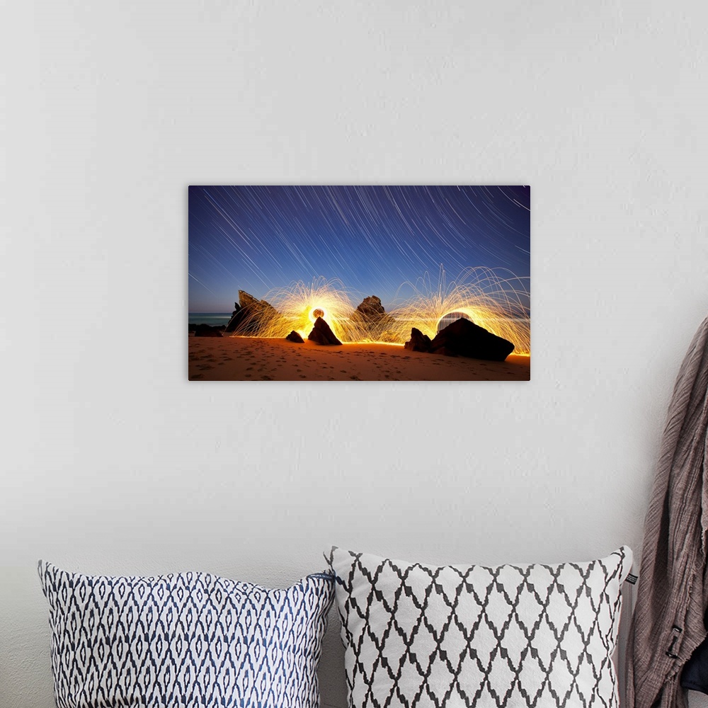 A bohemian room featuring Landscape photo of Praia da Adraga, Portugal at night with star trails in the sky and firework li...