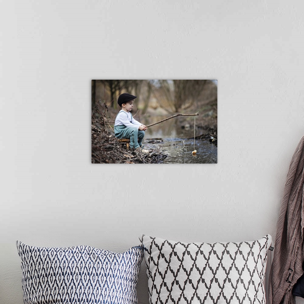 A bohemian room featuring Portrait of a young boy at the edge of a stream with a simple fishing rod.