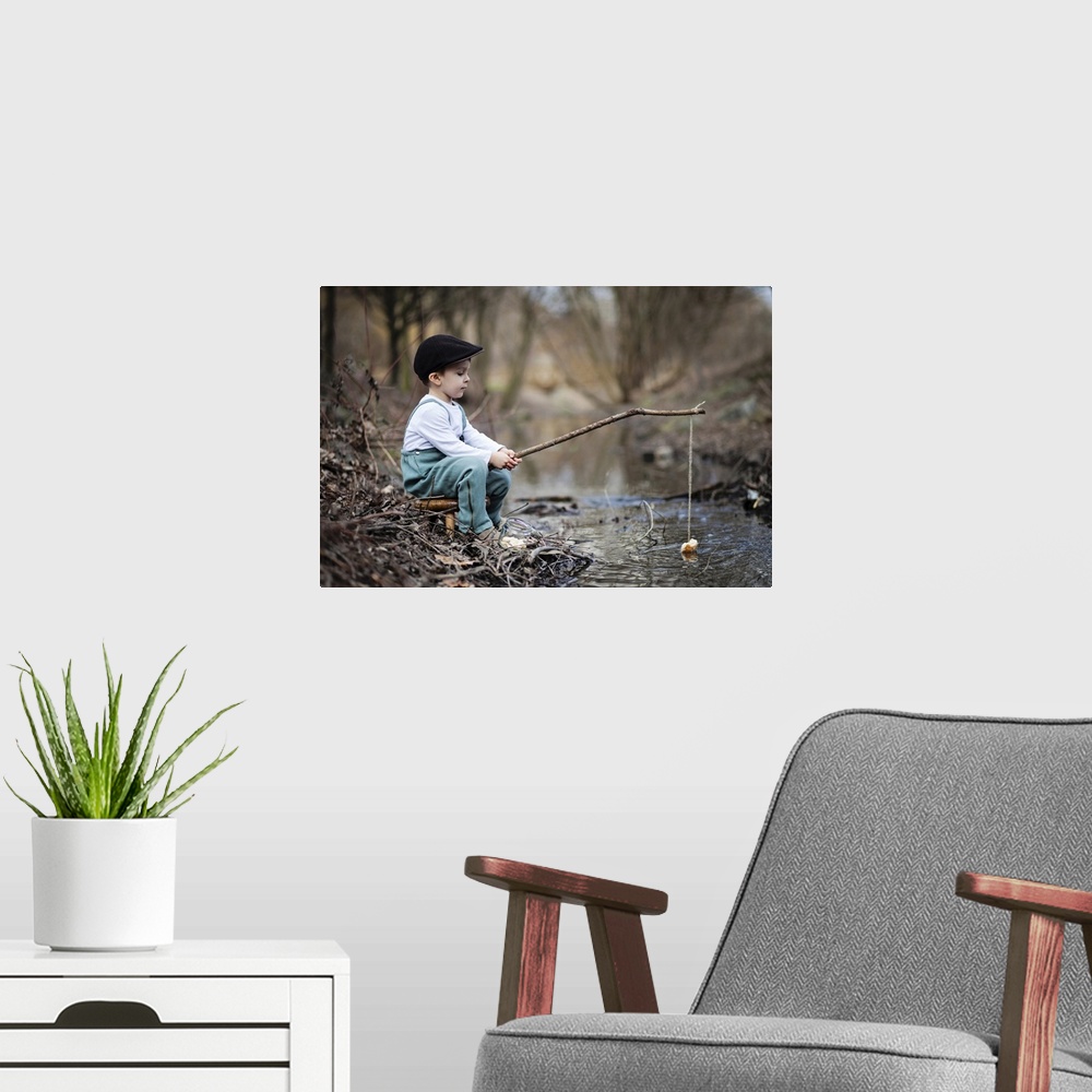 A modern room featuring Portrait of a young boy at the edge of a stream with a simple fishing rod.