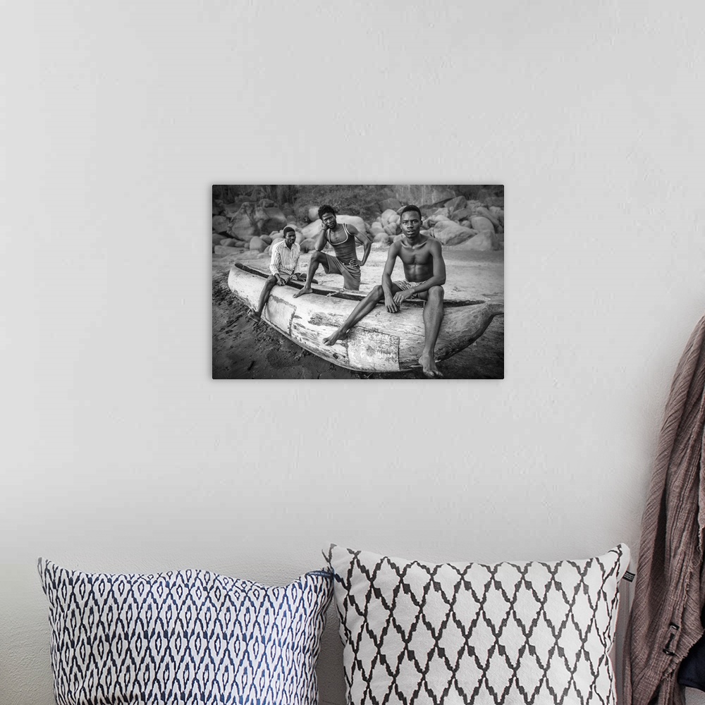 A bohemian room featuring Three fishermen from Malawi posing with their canoe on the beach.