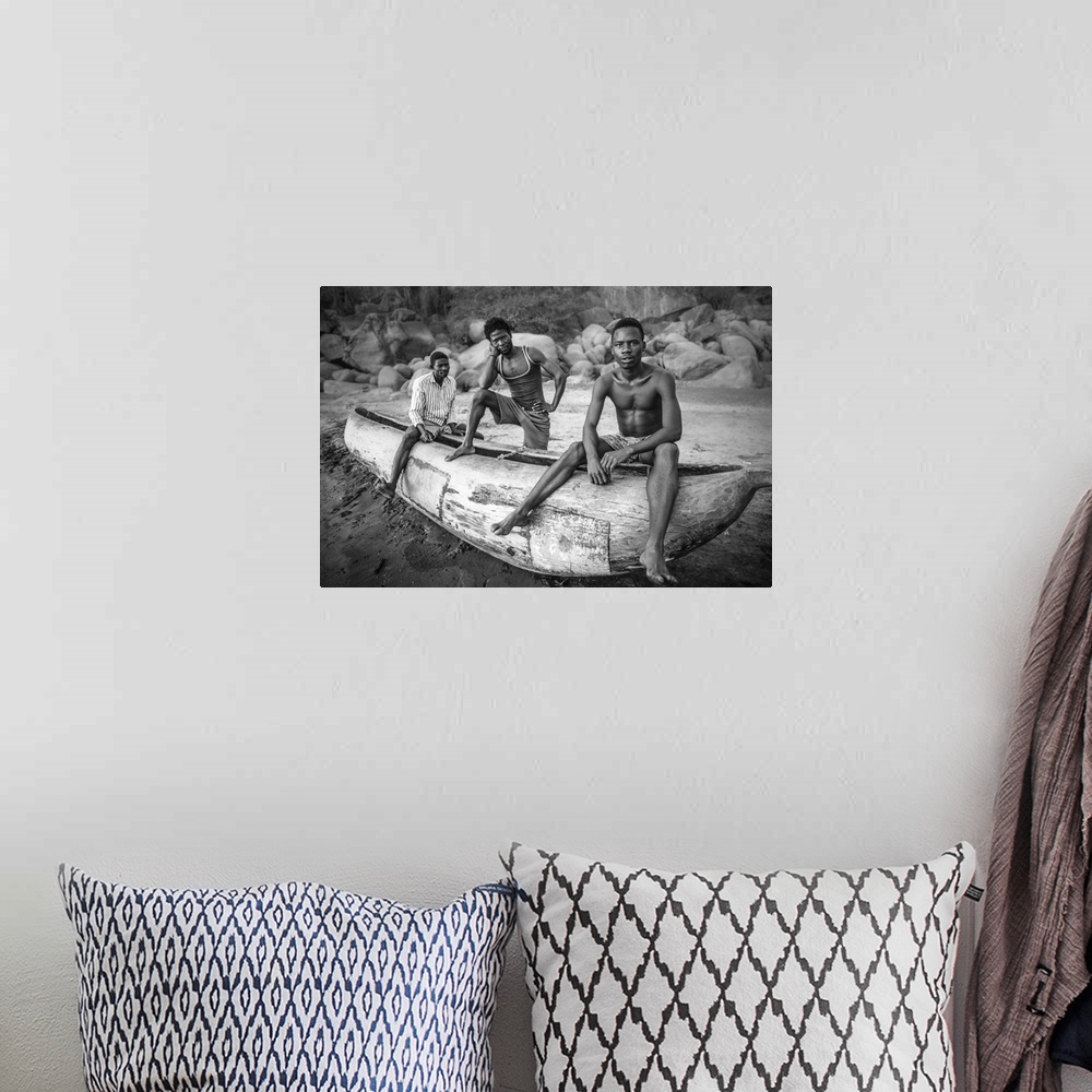 A bohemian room featuring Three fishermen from Malawi posing with their canoe on the beach.