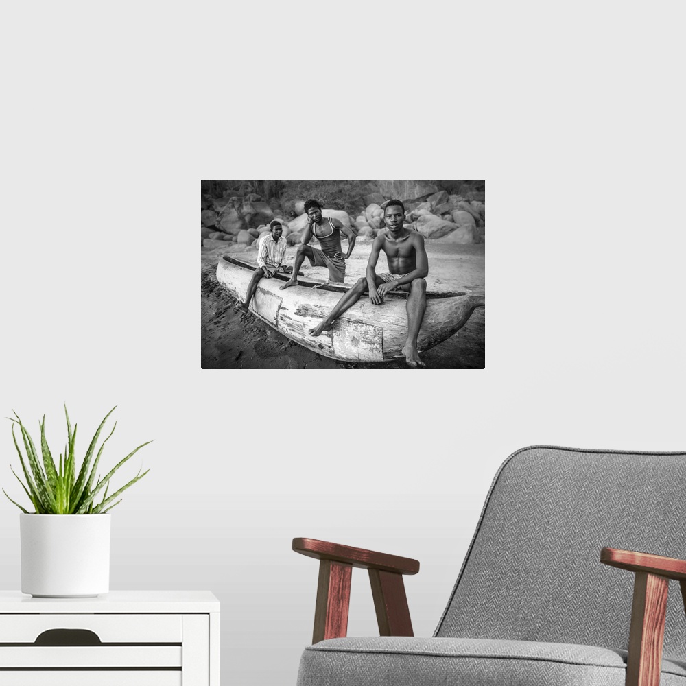 A modern room featuring Three fishermen from Malawi posing with their canoe on the beach.