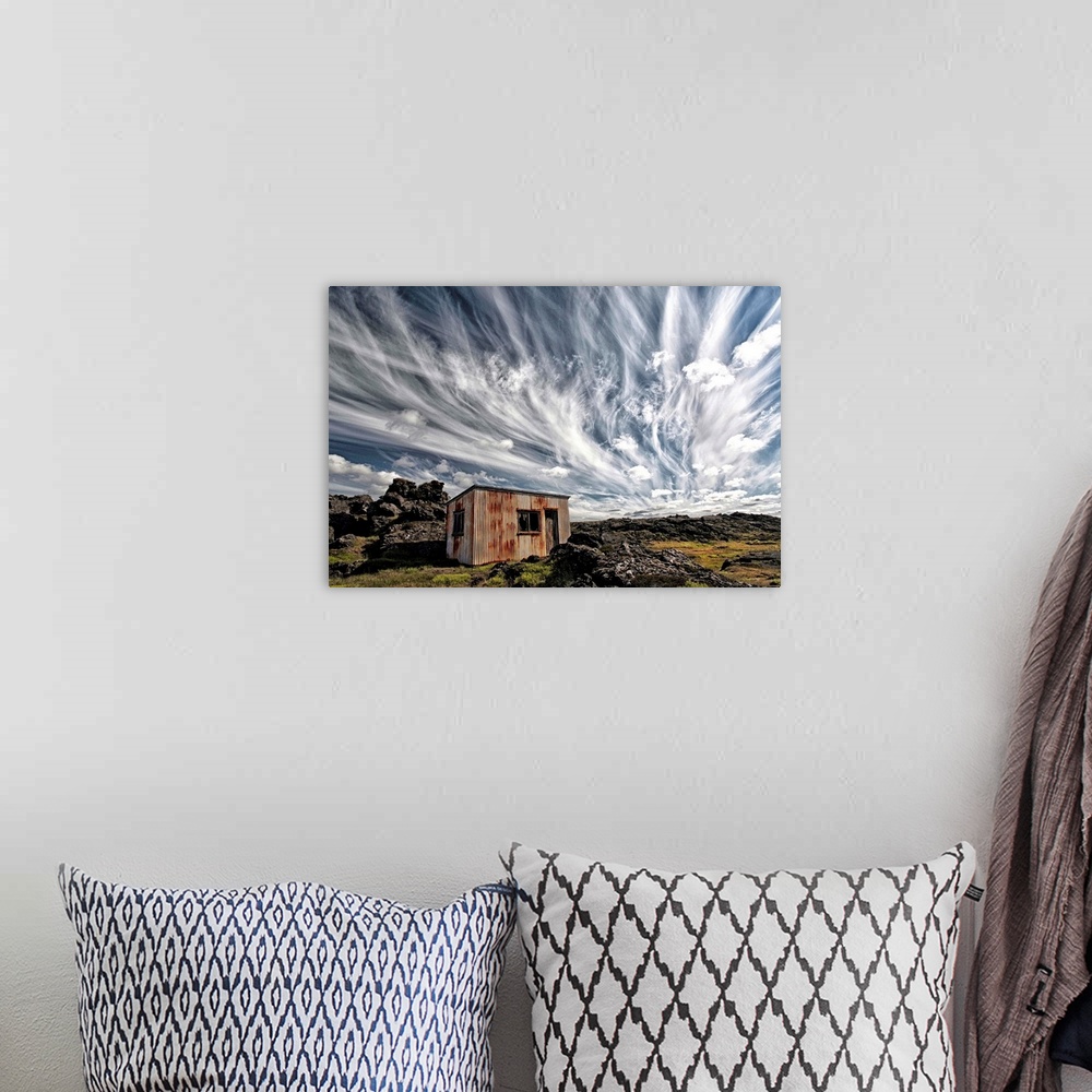 A bohemian room featuring A dramatic skyscape over a derelict shack in the Icelandic countryside.
