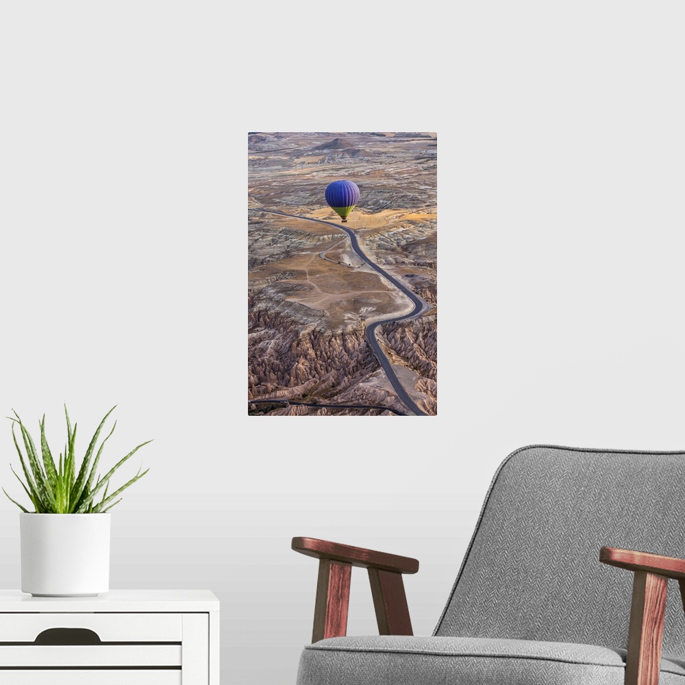 A modern room featuring A blue hot air balloon flying high above a rugged and arid looking landscape.