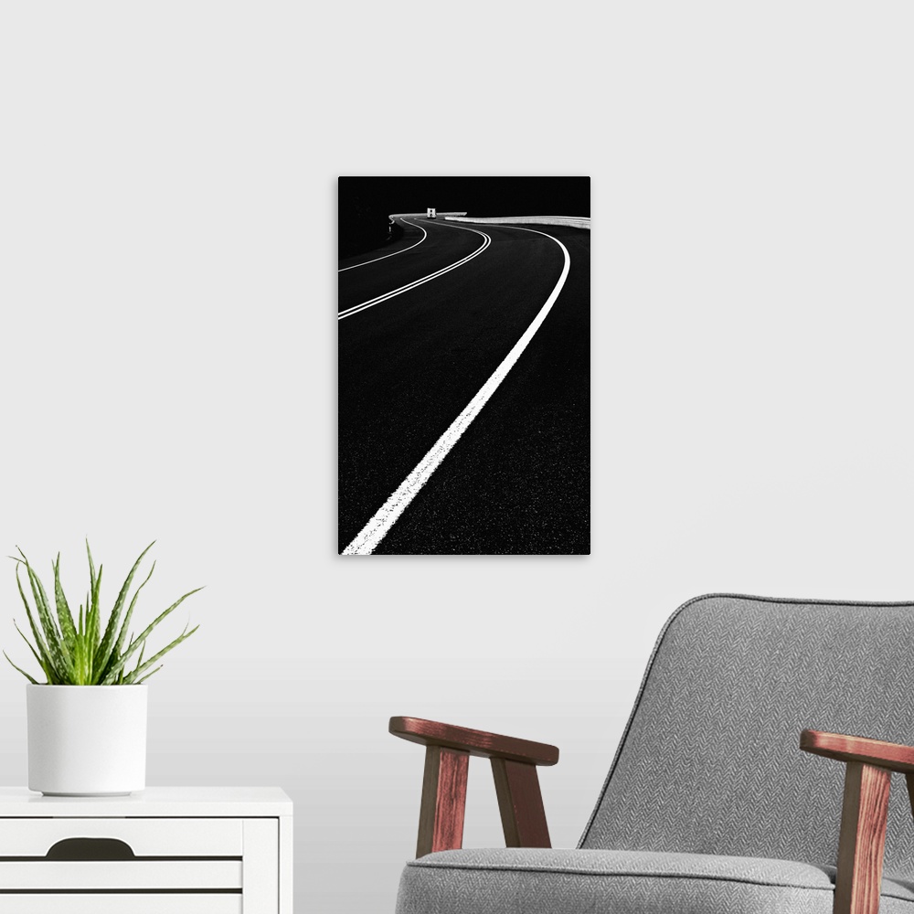 A modern room featuring High contrast black and white image of lines on a road curving around a bend.