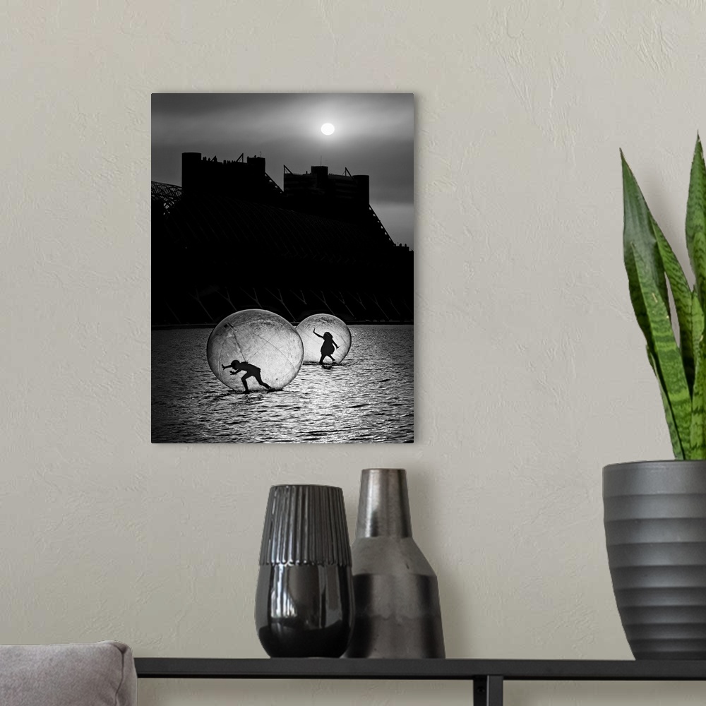A modern room featuring Two human bubbles housing silhouetted figures treading along a watery surface under moonlight.