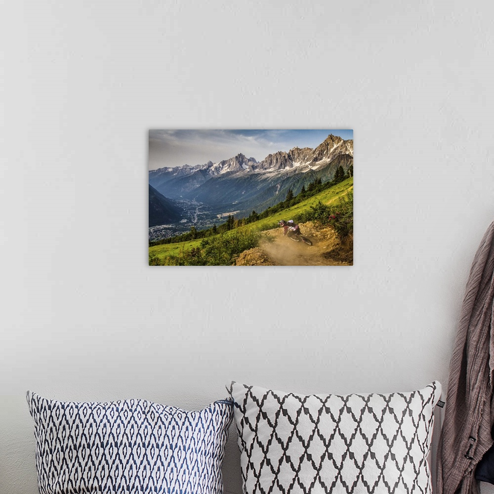 A bohemian room featuring A mountain biker kicking up dust from while riding a trail, with a spectacular mountain range in ...