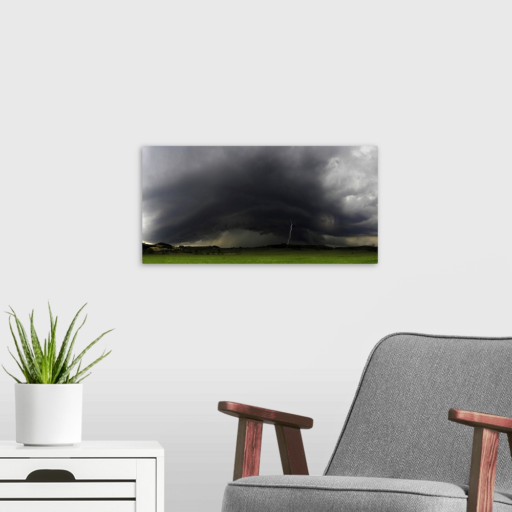 A modern room featuring "Rolling Thunderstorms," a bolt of lightning strikes the ground from dark stormclouds over a gree...
