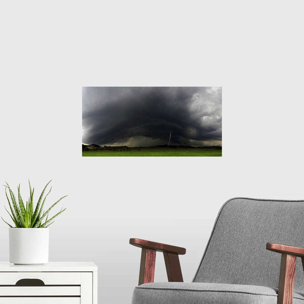 A modern room featuring "Rolling Thunderstorms," a bolt of lightning strikes the ground from dark stormclouds over a gree...