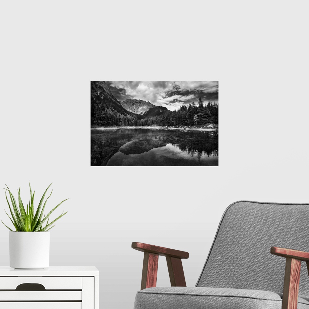 A modern room featuring A black and white photograph of a wilderness scene with a mountain range and forest reflecting in...