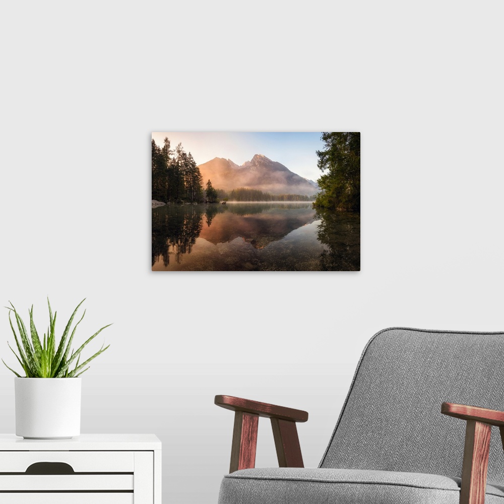 A modern room featuring Reflective landscape photograph on a lake with trees and mountains in the background at sunrise.