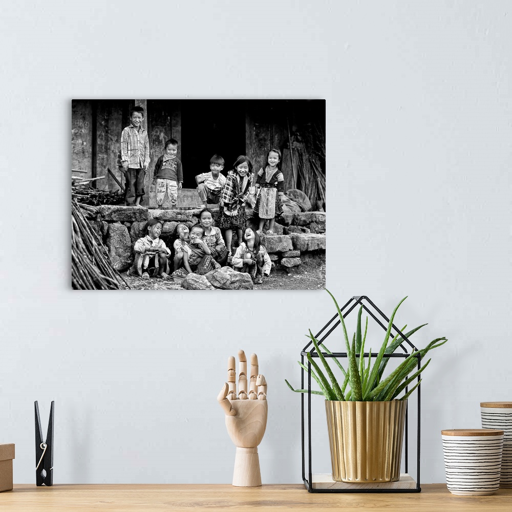 A bohemian room featuring A group of smiling children standing in front of a house in Vietnam.