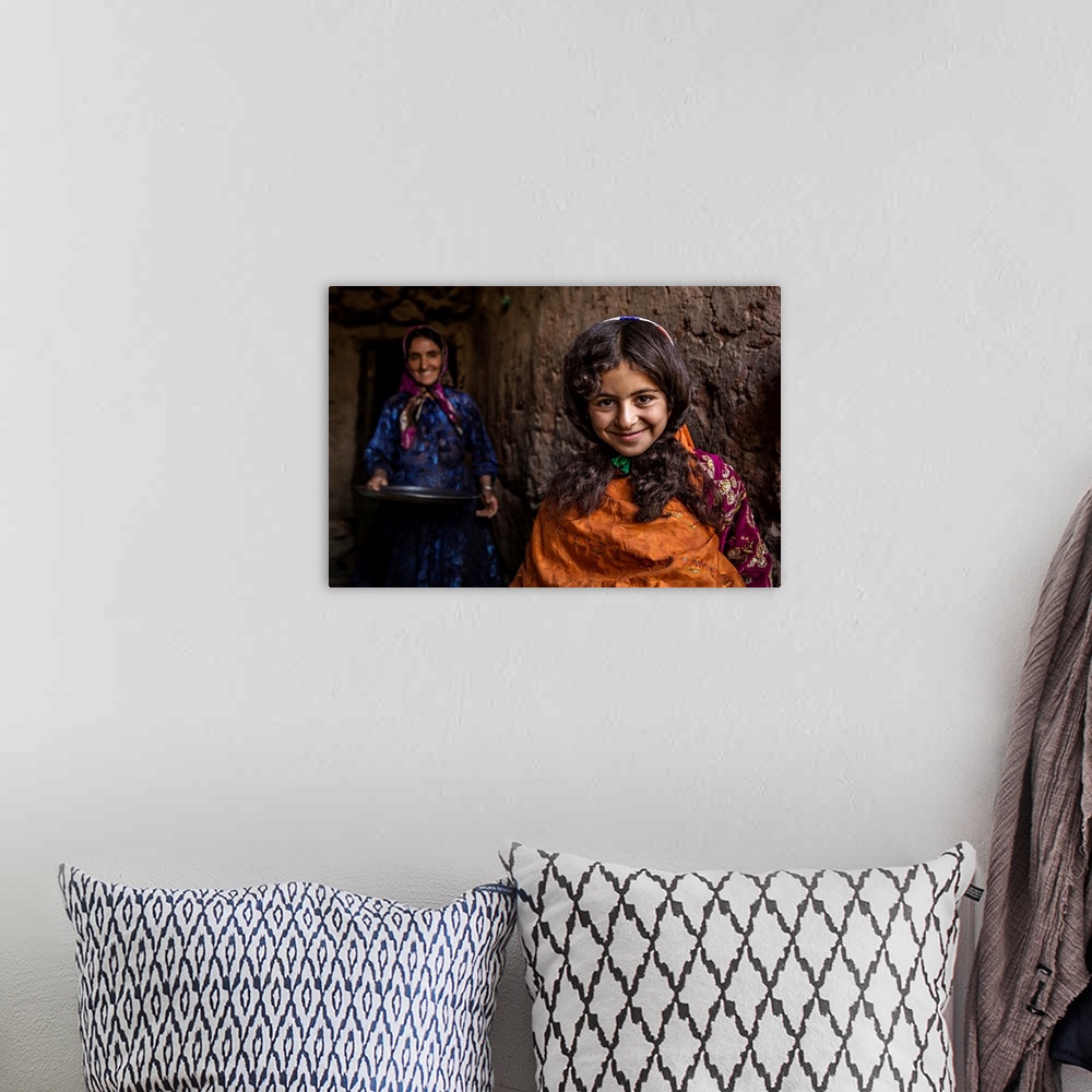 A bohemian room featuring A smiling young girl with her mother standing behind her, Iran.