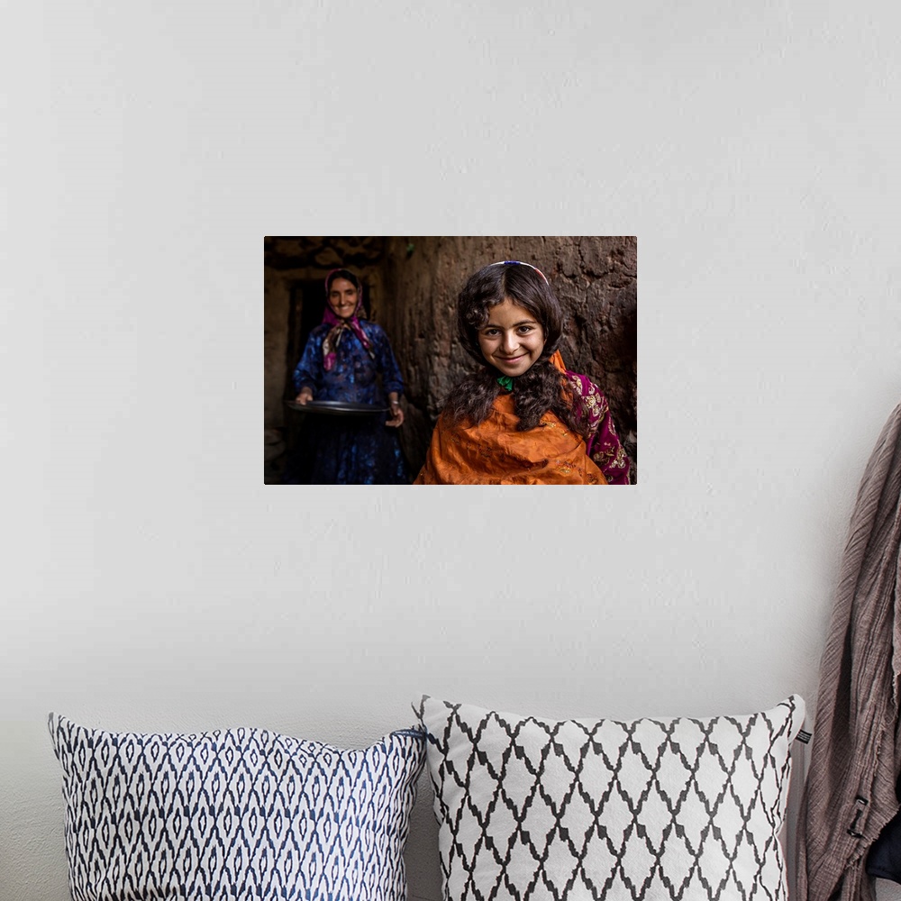 A bohemian room featuring A smiling young girl with her mother standing behind her, Iran.