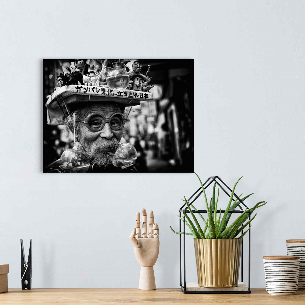 A bohemian room featuring Humorous portrait of a man wearing an odd hat constructed of figurines and live goldfish in bowls.