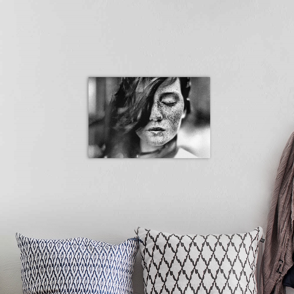 A bohemian room featuring Black and white portrait of a young girl with freckles and hair covering one of her eyes.