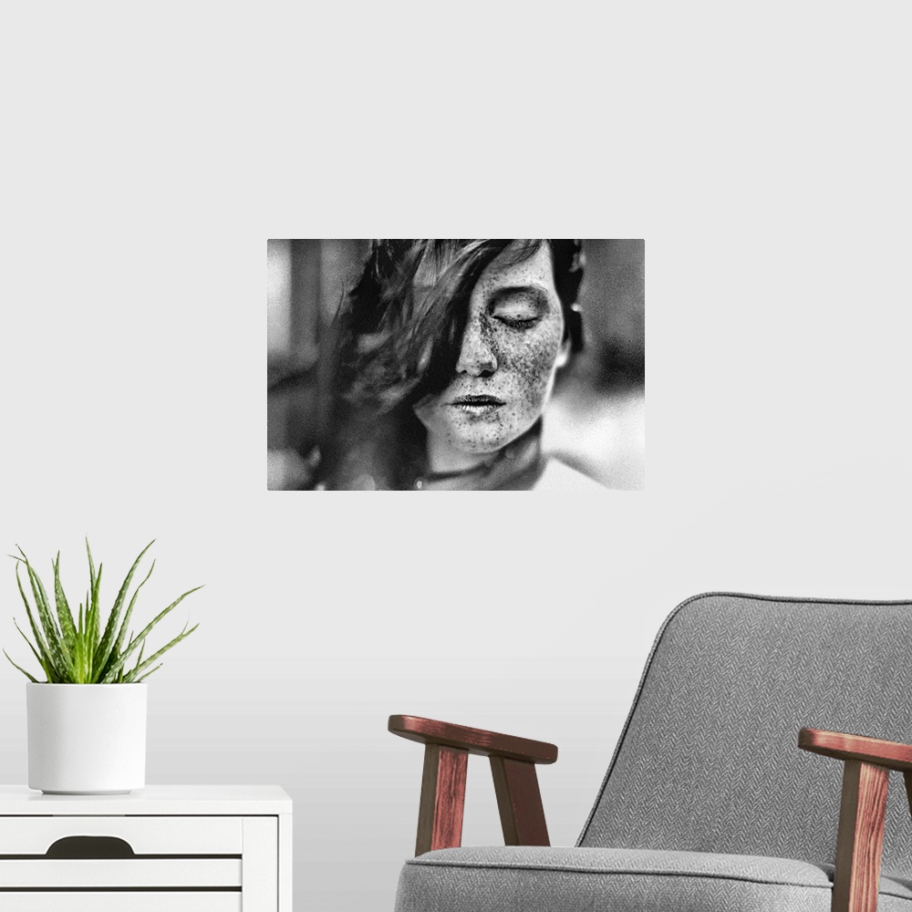 A modern room featuring Black and white portrait of a young girl with freckles and hair covering one of her eyes.