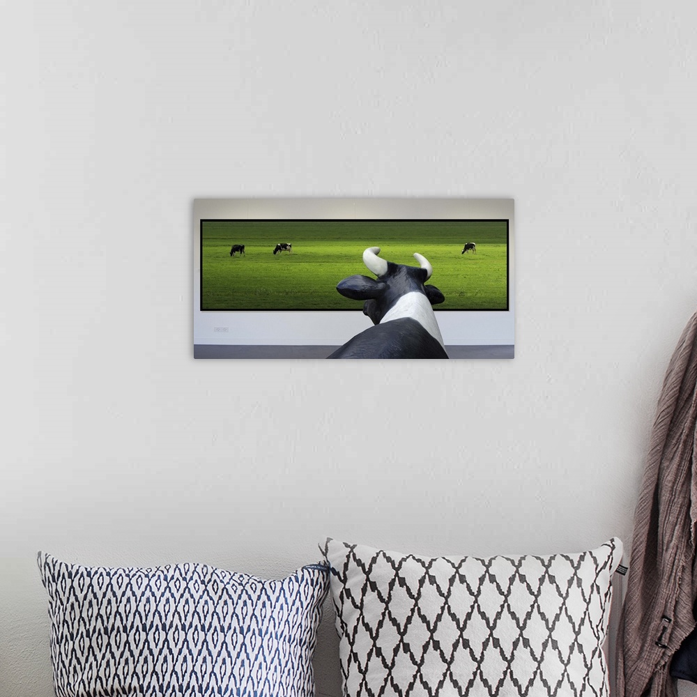 A bohemian room featuring Conceptual image of a cow looking at a framed photo of other cows in a green field.