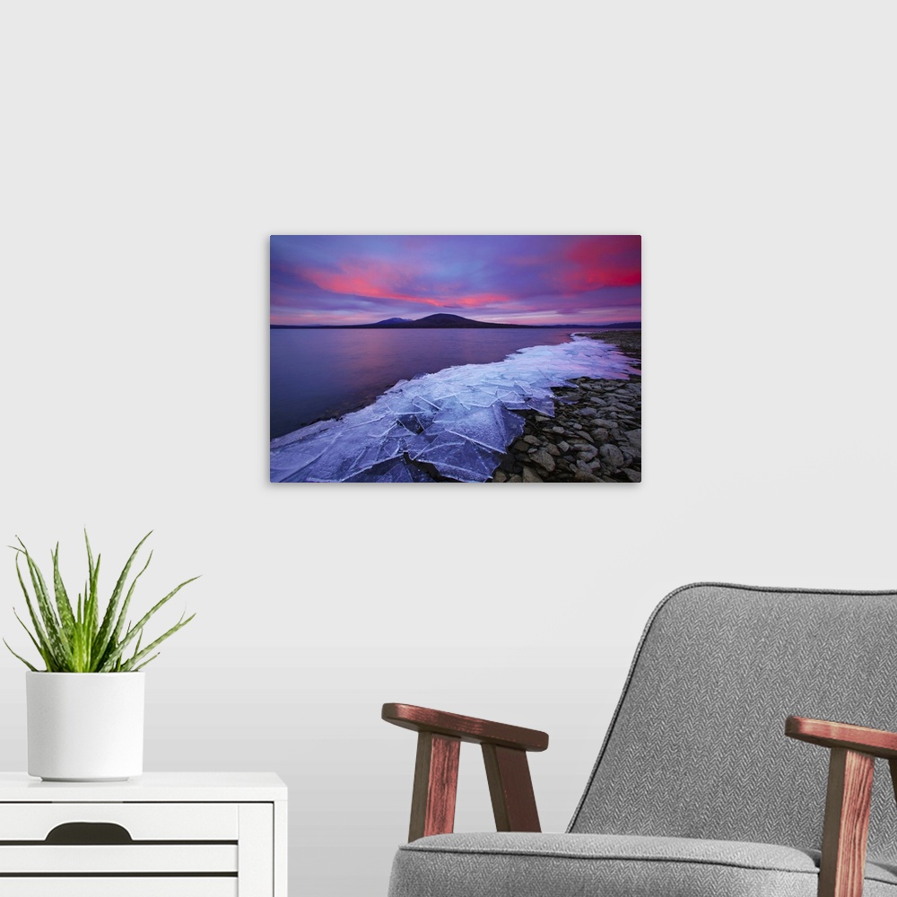 A modern room featuring Cracked ice sheets on a rocky shore at sunrise.