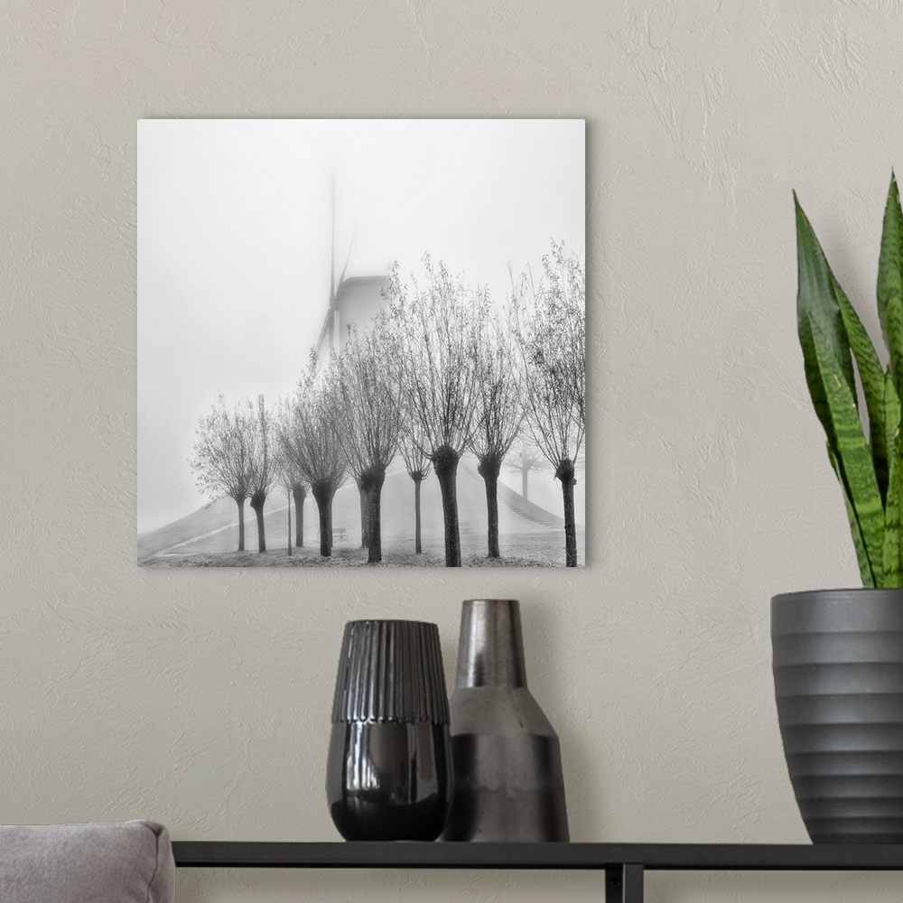 A modern room featuring A row of trees obscuring a windmill in the fog, Bruges, Belgium.