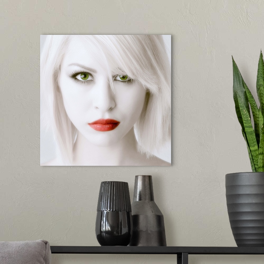 A modern room featuring Portrait of a woman with stark white skin and hair, large green eyes, and red lips.