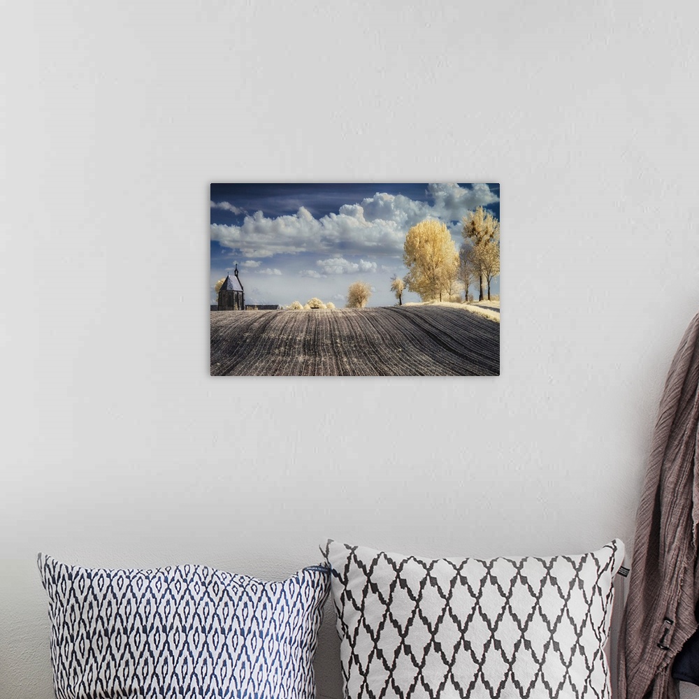 A bohemian room featuring Infrared image of a tilled field in the countryside in Poland, with a church and trees.