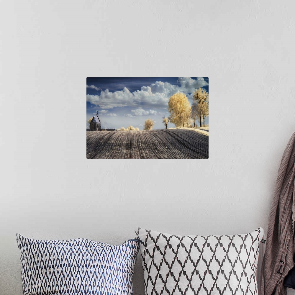 A bohemian room featuring Infrared image of a tilled field in the countryside in Poland, with a church and trees.