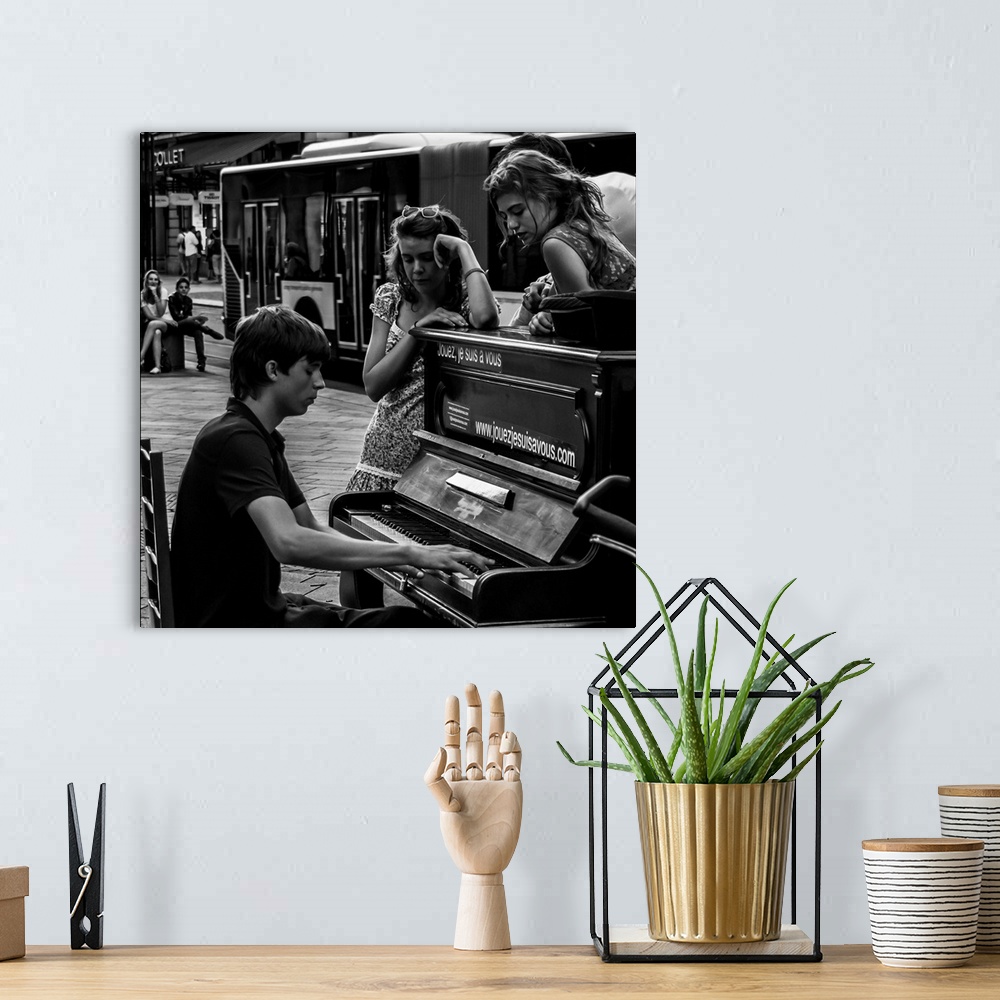 A bohemian room featuring A black and white photograph of a man playing a piano in the street and women sitting around list...