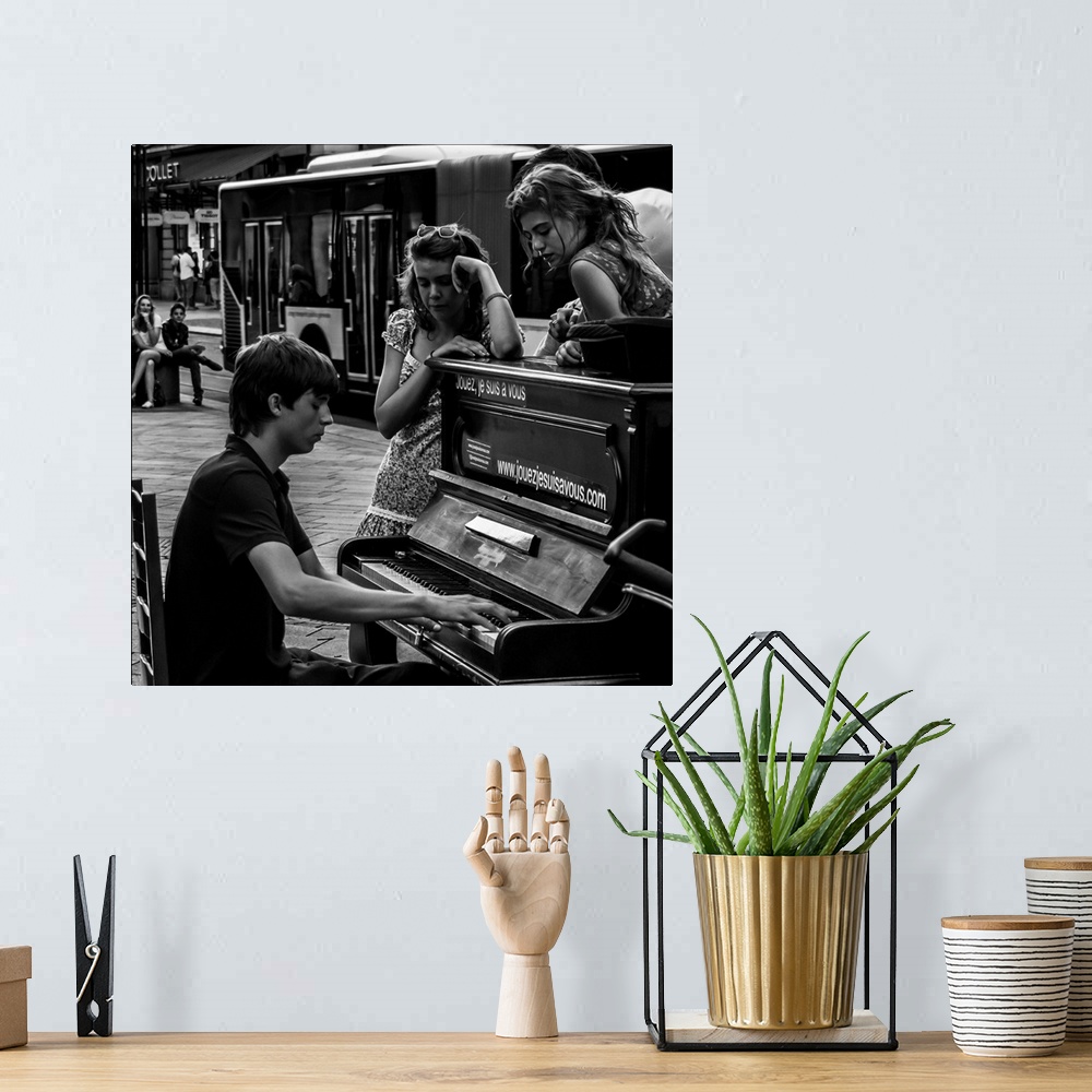 A bohemian room featuring A black and white photograph of a man playing a piano in the street and women sitting around list...