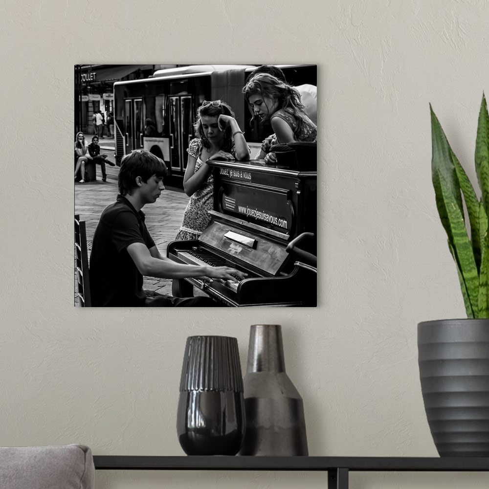 A modern room featuring A black and white photograph of a man playing a piano in the street and women sitting around list...