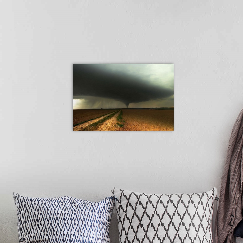A bohemian room featuring A tornado extends into the horizon from storm-clouds overhead, seen from across farmland.