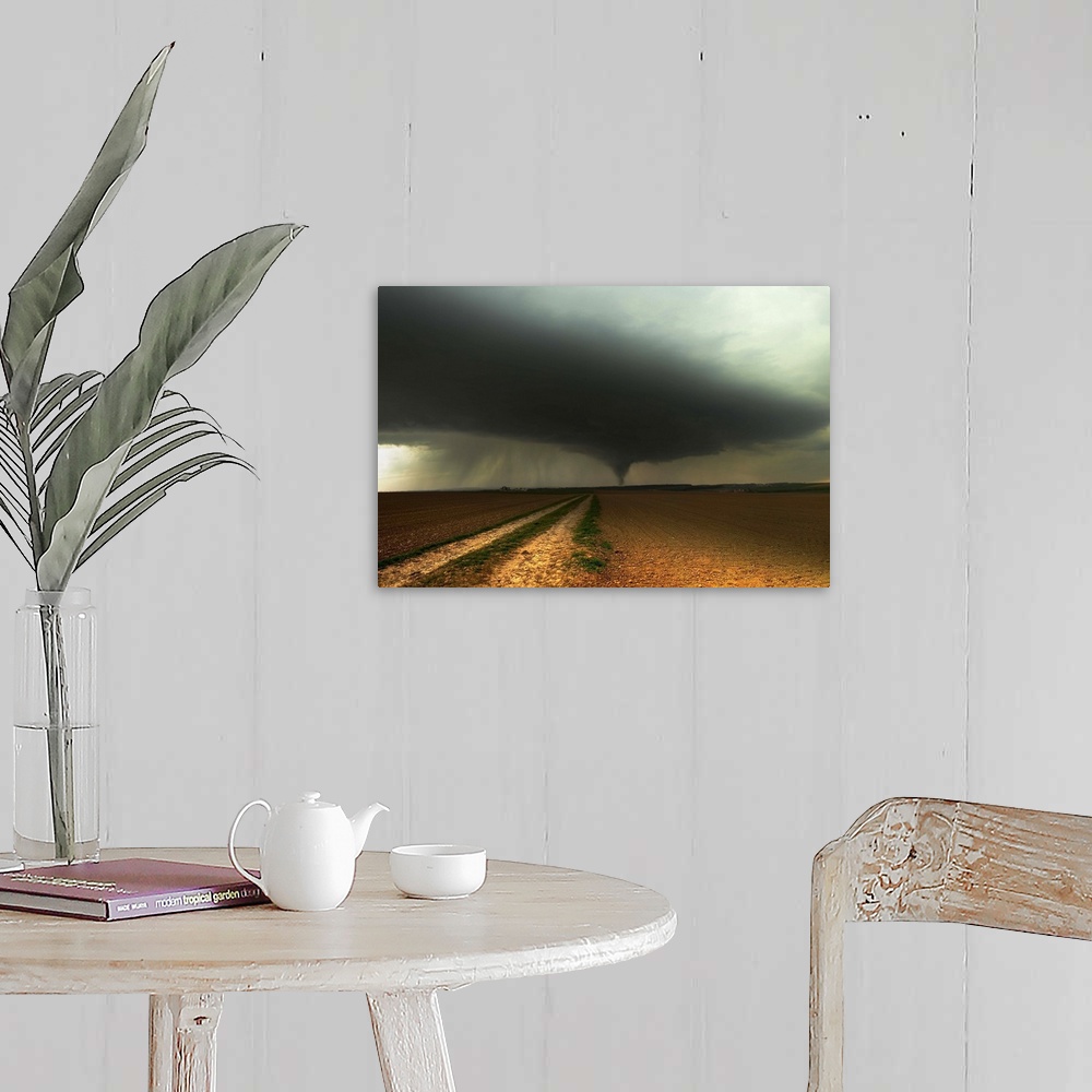 A farmhouse room featuring A tornado extends into the horizon from storm-clouds overhead, seen from across farmland.
