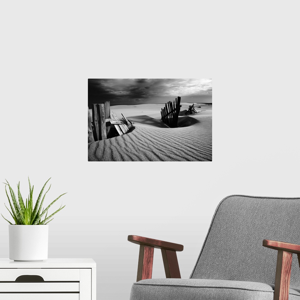 A modern room featuring Black and white photograph of a fence at the White Sands dunes in the Curonian Spit.
