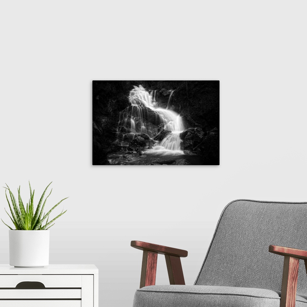 A modern room featuring High contrast image of a waterfall cascading down smooth rocks in a cliff.