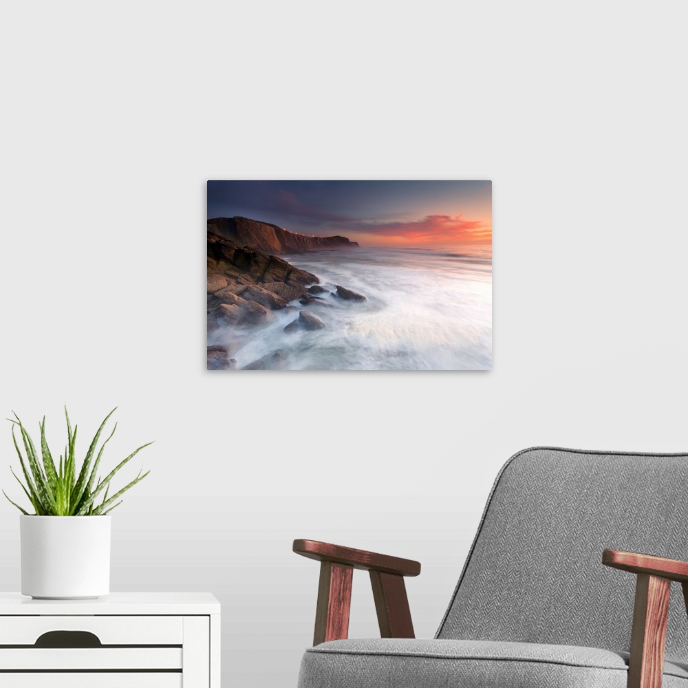 A modern room featuring Rocky ocean cliffs over the sea at sunset, Santa Cruz, Portugal.
