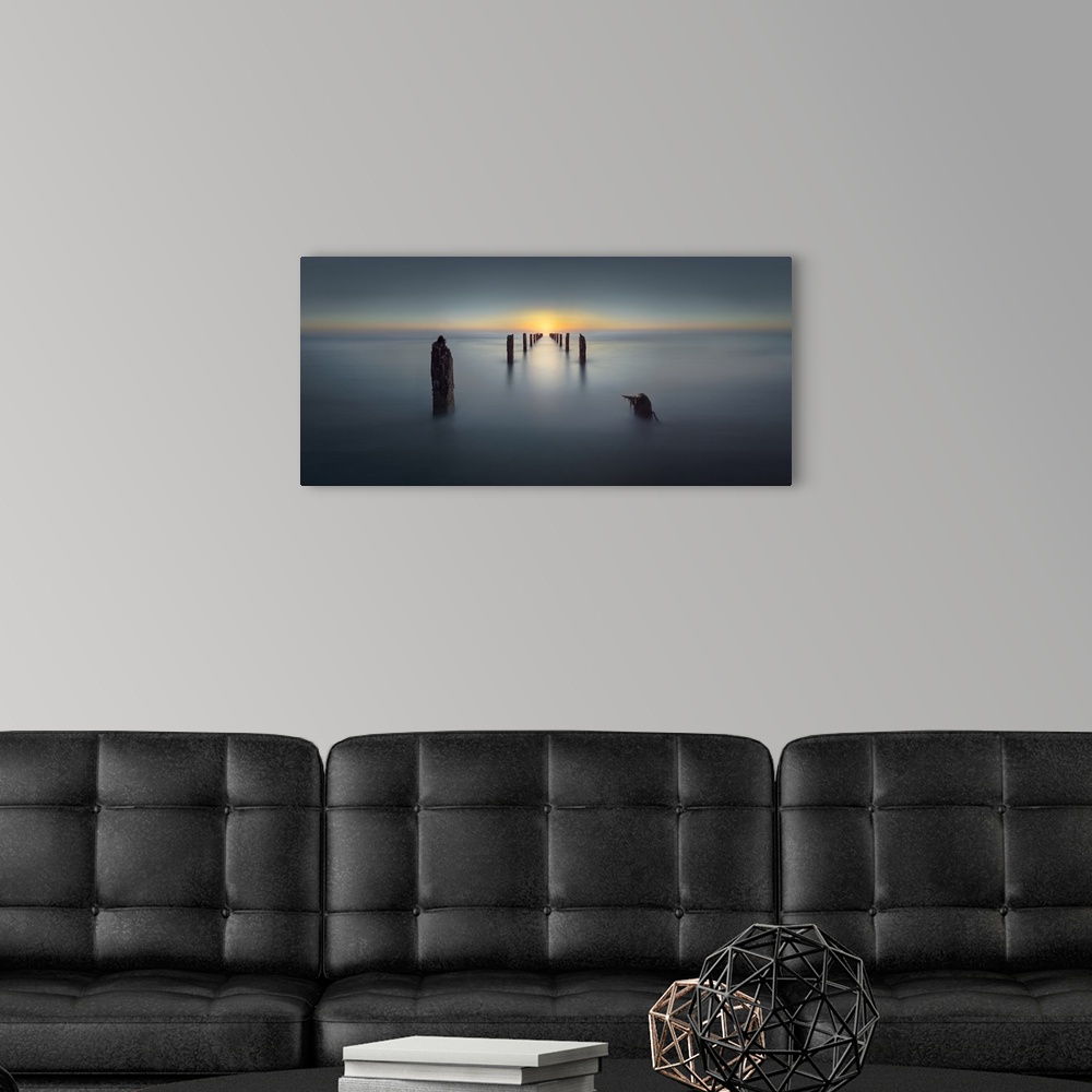 A modern room featuring Remains of a pier jetting out into the water with the sun setting in the distance.
