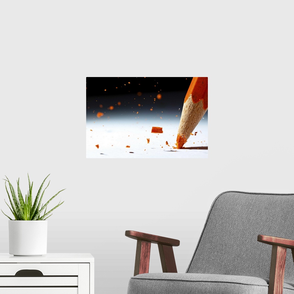 A modern room featuring Close up image of the lead of an orange colored pencil shattering.