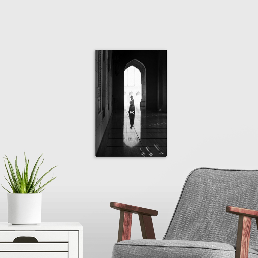 A modern room featuring A photograph of a man and architectural interior casting reflections on the floor.