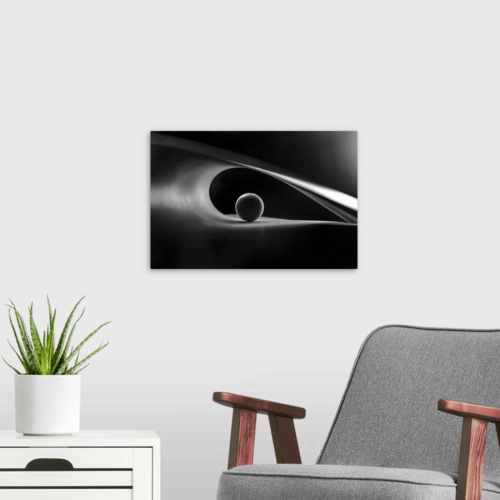 A modern room featuring A still-life of a golf ball in the curve of an abstract shape.