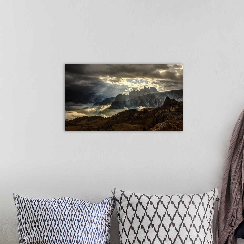 A bohemian room featuring Ray of sunlight shining through the clouds onto the peaks of the Dolomites.